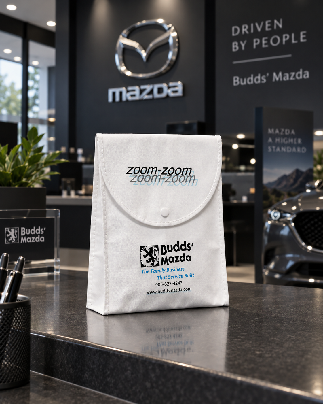 White custom printed shopping bag photographed outside a Budds' Mazda dealership